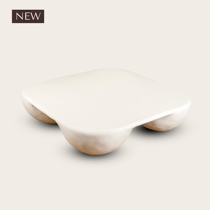 Plaster coffee table with four ball feet on a white background